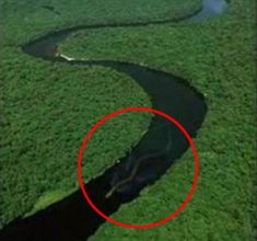 an aerial view of a river in the middle of green grass with a red circle over it