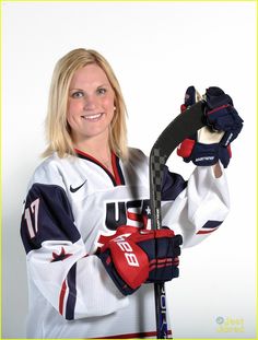 a female hockey player posing for a photo with her glove and mitt in hand