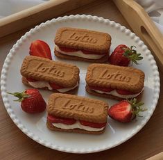 four cookies and strawberries on a plate with the word love spelled in small letters