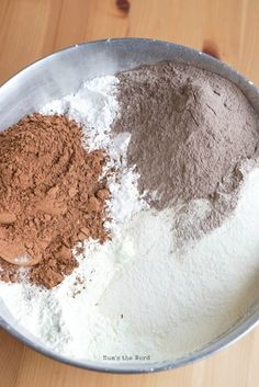 three different types of powder in a metal bowl on a wooden table with a spoon