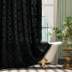 a bath tub sitting next to a window covered in black and white curtains