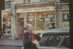 an older woman walking down the street in front of a store