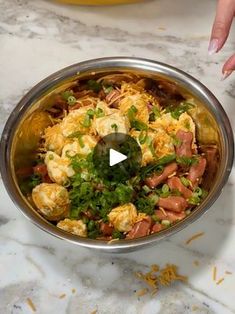 a bowl filled with food on top of a counter next to a person's hand