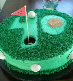 a cake that looks like a hole in the grass with a flag on it and golf balls