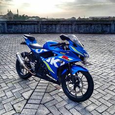 a blue motorcycle parked on top of a cobblestone road