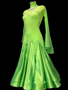 a green ballroom dress on display in front of a black background