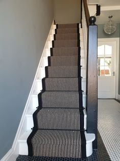 a stair case with black and white striped carpet on the bottom, next to an open door