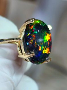 Large black fire opal with a large floral pattern among others, very bright and colorful. Very deep and dark  stone, 14x20mm, 12cts .  Mounted on a very sturdy and heavy, solid 14k yellow gold ring size 7, But can be made in any size 4 through 9 including halfs and quarters, nice choice for active people. The prongs can be done anyway you like, claw, flat, square etc. I'm always at the shop from late afternoon until late at 🌙 EST. so don't be afraid to contact me and talk about what you would like in your ring. Black Opal Rings, Opal Ring Engagement, Dreamy Jewelry, Black Opal Jewelry, Engagement Ring Black, Black Fire Opal, Natural Opal Ring, Black Opal Ring, Jewelry Opal