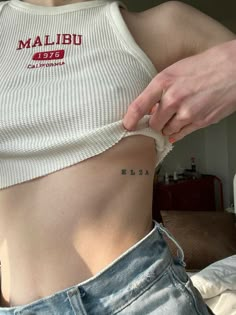 a woman is showing off her stomach with the word feminine on it's side