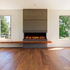 an empty room with wood floors and a fire place in the center, surrounded by windows