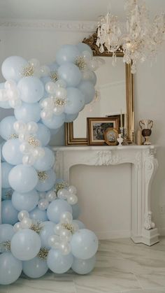 blue and white balloons are floating in the air next to a fireplace with a chandelier