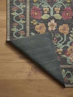 an area rug with flowers on it laying on the floor next to a piece of wood