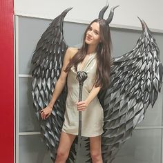 a woman standing in front of a wall with wings on it