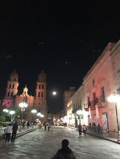 people are walking down the street at night