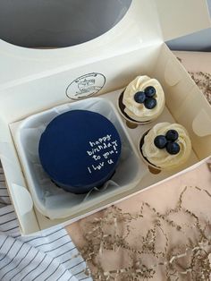 three cupcakes in a box with blue frosting