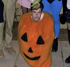 a man in a pumpkin costume sitting on the ground