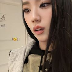 a woman with long black hair wearing a gray sweater and gold stud earrings on her left ear