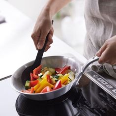 a person cooking vegetables in a pan on the stove