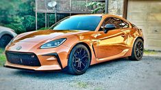 an orange sports car parked in front of a garage