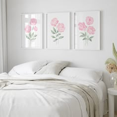 a bed with white sheets and pink flowers on the wall above it in a bedroom