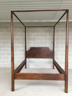 a wooden bed frame sitting in front of a brick wall with white bricks on it