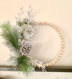 a wreath with pine cones and branches on a mantle