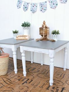 two tables with plants on them in front of a white wall and wood flooring