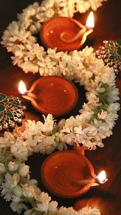 three candles are lit in front of some flowers