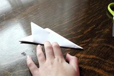 someone is cutting out a paper airplane on a table next to scissors and a pair of scissors