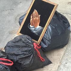 there is a painting on the ground next to trash bags and black bags that have been placed in front of it