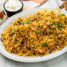 a white plate topped with yellow rice and garnished with cilantro