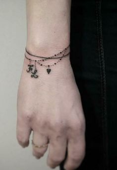 a woman's arm with a anchor and heart tattoo on it, while wearing a black bracelet