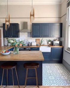 a kitchen with blue cabinets and counter tops, two stools in front of the island