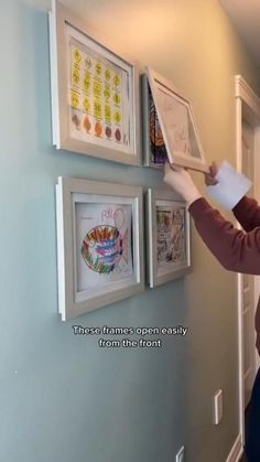 a woman is holding a piece of paper in front of some pictures on the wall