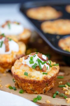 some food that is sitting on top of a cutting board with green onions and sour cream