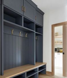 an empty room with blue cabinets and wooden benches in the center, next to a door