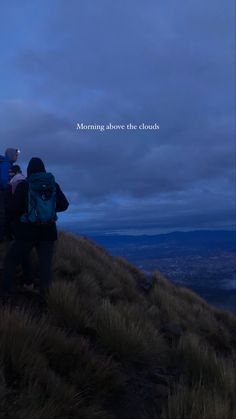 two people standing on top of a hill at night with the words morning above the clouds