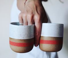 a person holding two cups in their hands