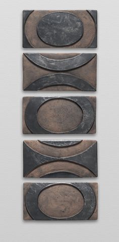 three pieces of metal on a white wall with black and brown circles in the middle