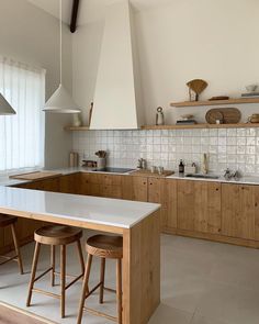 a kitchen with wooden cabinets and white counter tops, two stools at the island