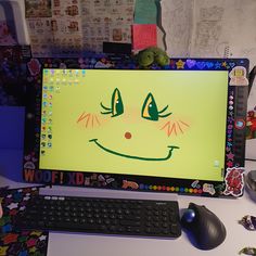 a computer screen with a smiley face drawn on it's side next to a keyboard and mouse