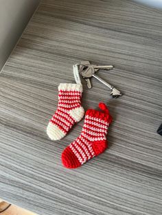 a pair of red and white knitted socks next to a key on a table