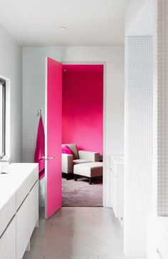 an open door leading to a bathroom with pink paint on the walls and white furniture