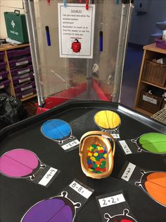 a black table topped with lots of different colored candies in front of a display case