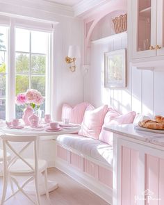 a white and pink kitchen with breakfast nooks on the table, flowers in vase