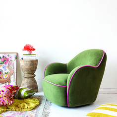 a green chair sitting on top of a white floor next to a vase and pictures