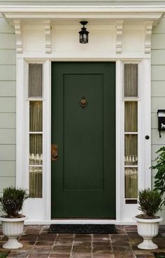 a green front door with two planters on either side