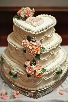 a three tiered wedding cake with flowers on it's sides and pearls around the edges