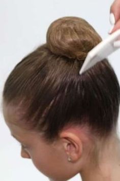 a woman is getting her hair done with a comb