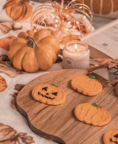 pumpkin shaped cookies sitting on top of a wooden board next to candles and other decorations